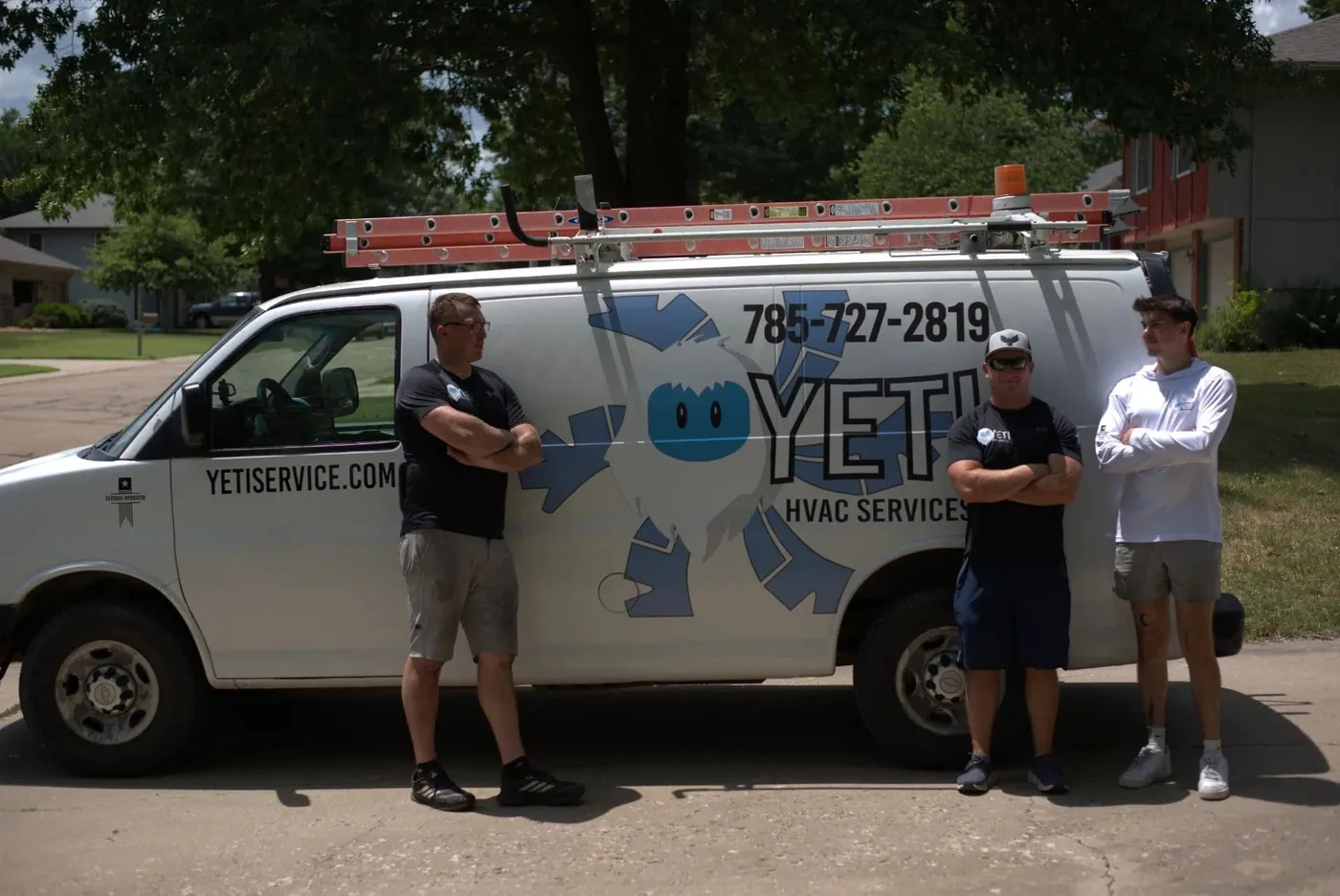 Three members of the Yeti HVAC team standing beside a white company van